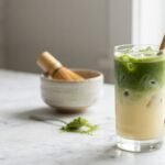 Glass of iced vanilla matcha latte recipe with green matcha over milk and ice