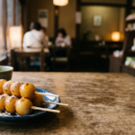 Tray of mitarashi and anko dango skewers beside a phone showing a dango near me map search
